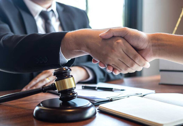 Two lawyers shaking hands with a gavel nearby